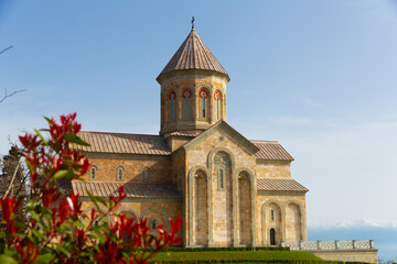 Fototapeta na wymiar Picturesque sunny spring landscape with Church of Saint Nino in Georgian Orthodox monastic complex at Bodbe near Sighnaghi town
