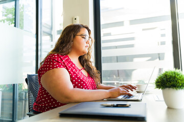 Profile view of a plus size woman using a laptop computer to read her emails in an office