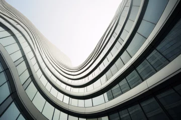 Fotobehang Modern building with wavy futuristic design, low angle view of abstract curve lines and sky. Geometric facade with glass and steel. Concept of architecture exterior, business, office © scaliger