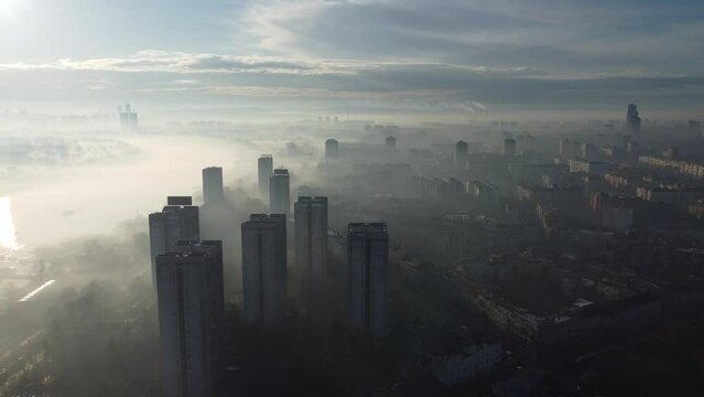 Drone flight above Belgrade city in the smog and fog in the morning. Zemun and New Belgrade district, Serbia, Europe.