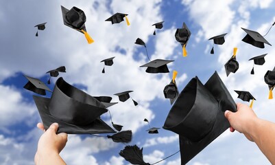 Graduating students throwing black graduation caps in sky