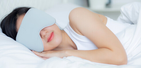 Fototapeta na wymiar Beautiful young asian woman wearing cover eye and sleeping on bed with head on pillow comfort and happiness in the bedroom at home, girl with relax and leisure for wellness, lifestyles concept.