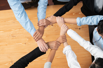 Multicultural business people holding hand together in circle. Unity teamwork in office business workplace. Diverse ethnic office worker engaged in team building. Habiliment