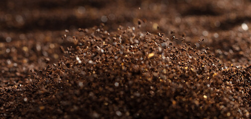 Ground Coffee roasted powder dust fly explosion, Coffee crushed ground float pouring. Roasted Coffee powder ground dust splash explosion in mid Air. Black background Isolated selective focus blur