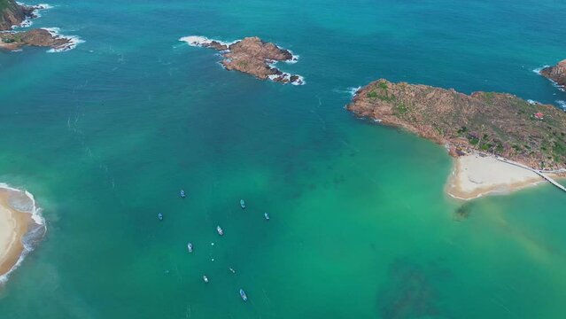 Aerial landscape at Hon Kho beach, Binh Dinh, Vietnam with clear blue beach and anchored fishing boats. Bay and island tourism and nature concept.