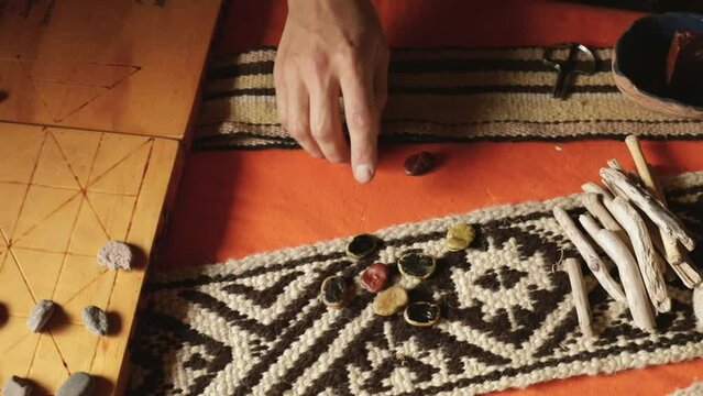 Traditional mapuche recreational games. Closeup view of a man playing Auarr-cuden mapuche game, similar to payana. He throws sliced beans.