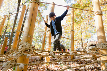 Boy walking on a rope play structure