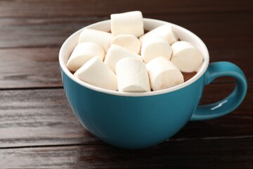 Fototapeta na wymiar Tasty hot chocolate with marshmallows on wooden table, closeup