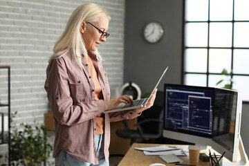 Mature female programmer working with laptop in office