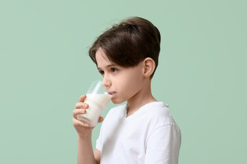Little boy drinking fresh milk on turquoise background