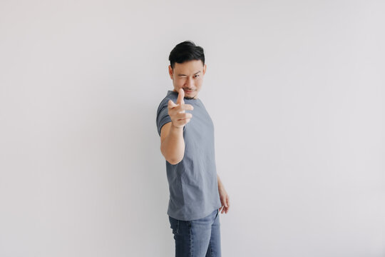 Happy asian man wears blue t-shirt and jeans winking at camera and smile.