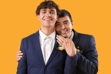 Married gay couple hugging on yellow background