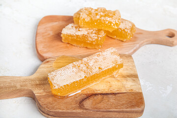 Wooden boards with fresh honeycombs on light background, closeup