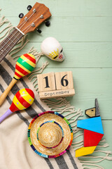 Cube calendar with date SEPTEMBER 16, maracas and Mexican decor on green wooden background. Mexico's Independence Day celebration