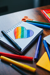 Photograph of notebook on wooden table with hand drawn LGBTQ+ heart. Concept of people and...