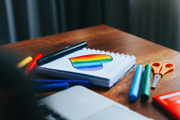 Photograph of notebook on wooden table with hand drawn LGBTQ+ heart. Concept of people and lifestyles.