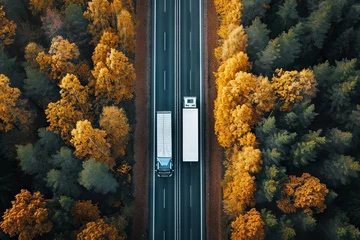 Foto op Canvas Drone captures autumnal forest road two trucks viewed from above © The Big L
