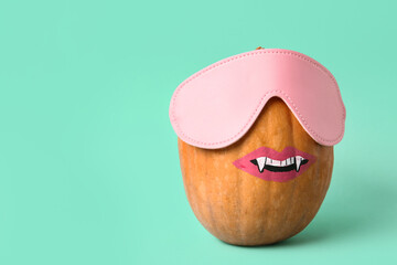 Funny Halloween pumpkin with drawn face and mask on turquoise background