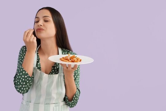 Young woman with tasty pasta on lilac background