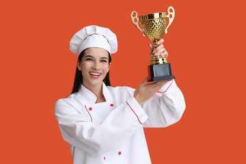 Female chef with gold cup on orange background