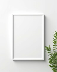 A close-up view of single, empty, white frame mockup on an isolated white wall, with decoration like green plant...