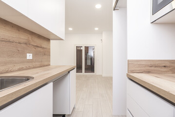 A small kitchen with smooth white furniture without handles