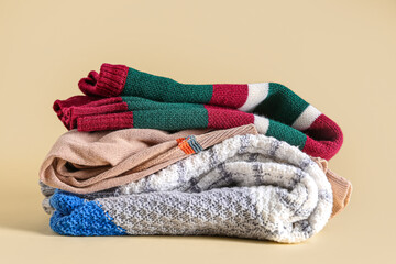 Stack of stylish sweaters on beige background