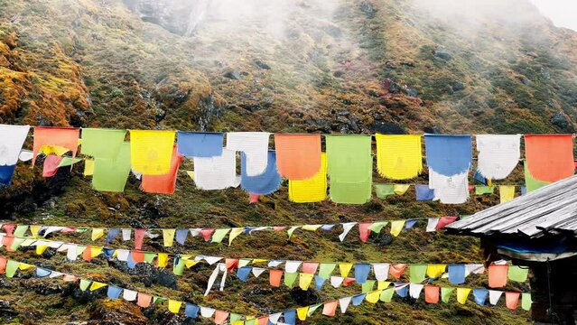 Holy buddhist praying multicolored flags with mantras flapping and waving on the  light wind slow motion 4K video with running foggy clouds in Tulikharka 4100m village on Mera peak climbing route.