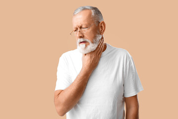 Ill old man with sore throat on beige background