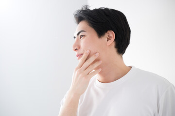 頬を触るアジア系（日本人）男性 爽やかな脱毛やスキンケアのイメージ クローズアップ メンズの美容やビューティーに - obrazy, fototapety, plakaty