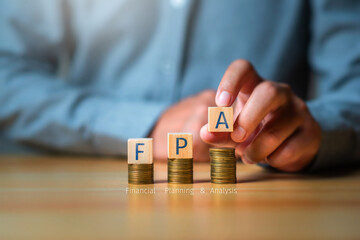 Financial planning and anlysis concept, Businessman put a cubic wood with word FPA on coinstack for personal financial planning, retirement plan.