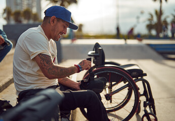 sporty disabled man sitting holding safety knee pads at skatepark
