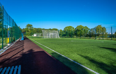 A football field with green grass outside the city near the forest. © Сергей Лаврищев