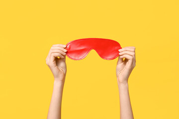 Female hands with mask from sex shop on yellow background