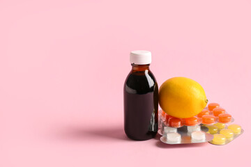 Pills for sore throat with cough syrup and lemon on pink background