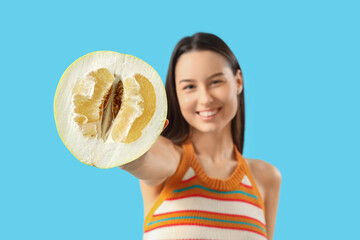 Pretty young woman with cut ripe pomelo on blue background