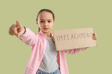 Protesting little girl holding placard with word IMPEACHMENT and pointing at viewer on green...