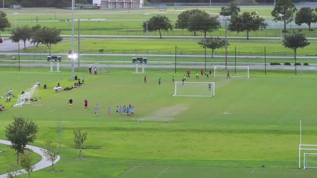 Schoolchildren playing football game on campus stadium in sports park.