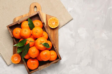 Wooden tray with sweet mandarins on grey background