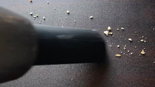 Vacuum cleaner cleaning smooth surface with biscuit crumbs on it
