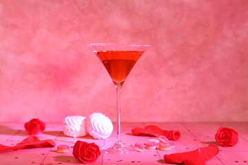 Glass of tasty cocktail with sweets, roses and balloons on tile table. Valentine's Day celebration