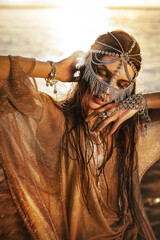 beautiful young tribal style woman outdoors at golden sunset - 716117532