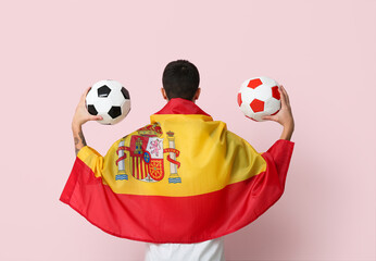 Young man with soccer balls and flag of Spain on pink background