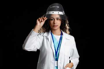 Female African-American medical intern in protective mask on black background