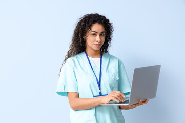 Female African-American medical intern using laptop on blue background