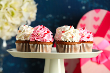 Stand with tasty cupcakes for Valentine's Day on blurred background