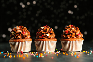 Tasty chocolate cupcakes with sequins for Valentine's Day on grey grunge table