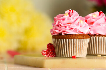 Board with tasty cupcakes for Valentine's Day on tile table