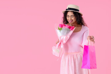 Fashionable African-American woman with bouquet of flowers and shopping bags on pink background. International Women's Day celebration