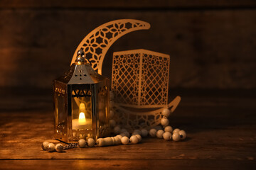 Muslim lamp with burning candle, decorative crescent and prayer beads for Ramadan on wooden table